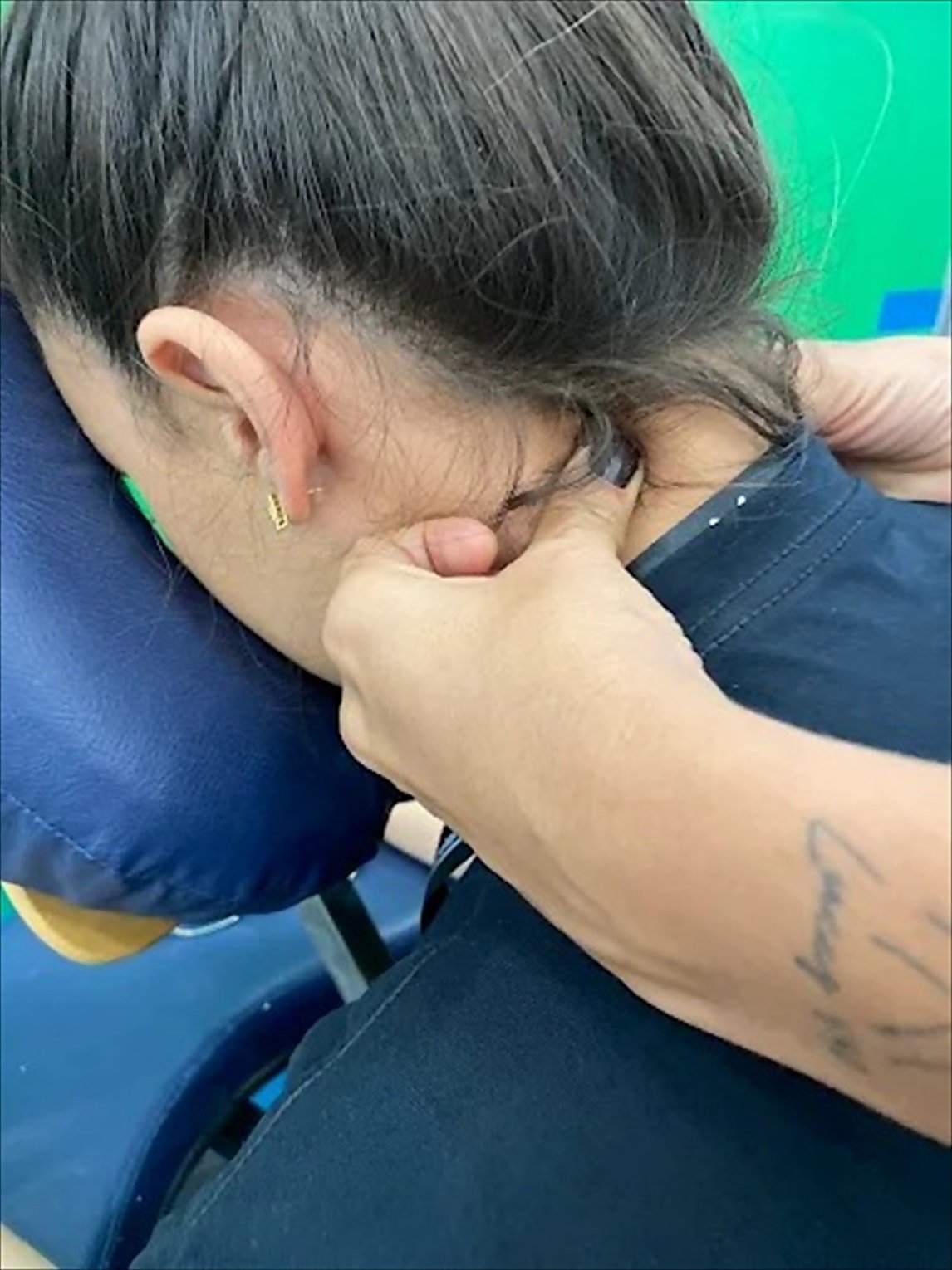 Mayra massageando o pescoço de uma cliente sentada na cadeira de quick massage